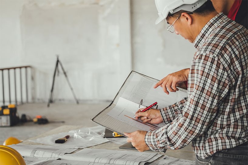 Two engineers reviewing and discussing drawings.