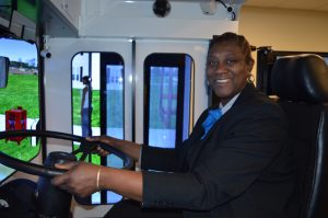 An employee demonstrating the use of the bus and snow plow simulator.