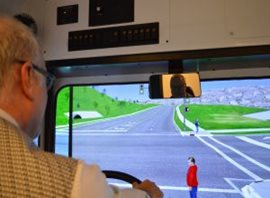 An employee demonstrating the use of the bus and snow plow simulator.